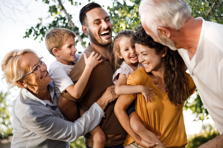 A family of grandparents, parents, and children huddled together and smiling.