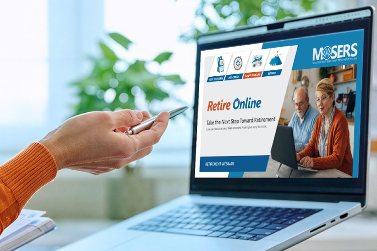 A person's hand holding a pen pointing toward a laptop screen with MOSERS Retire Online-Take the Next Step Toward Retirement.