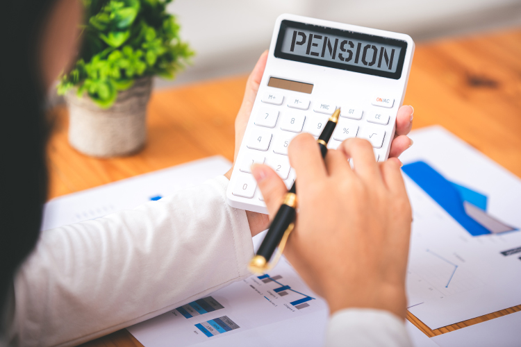 Charts and graphs on a table with a woman using a calculator that displays "PENSION".